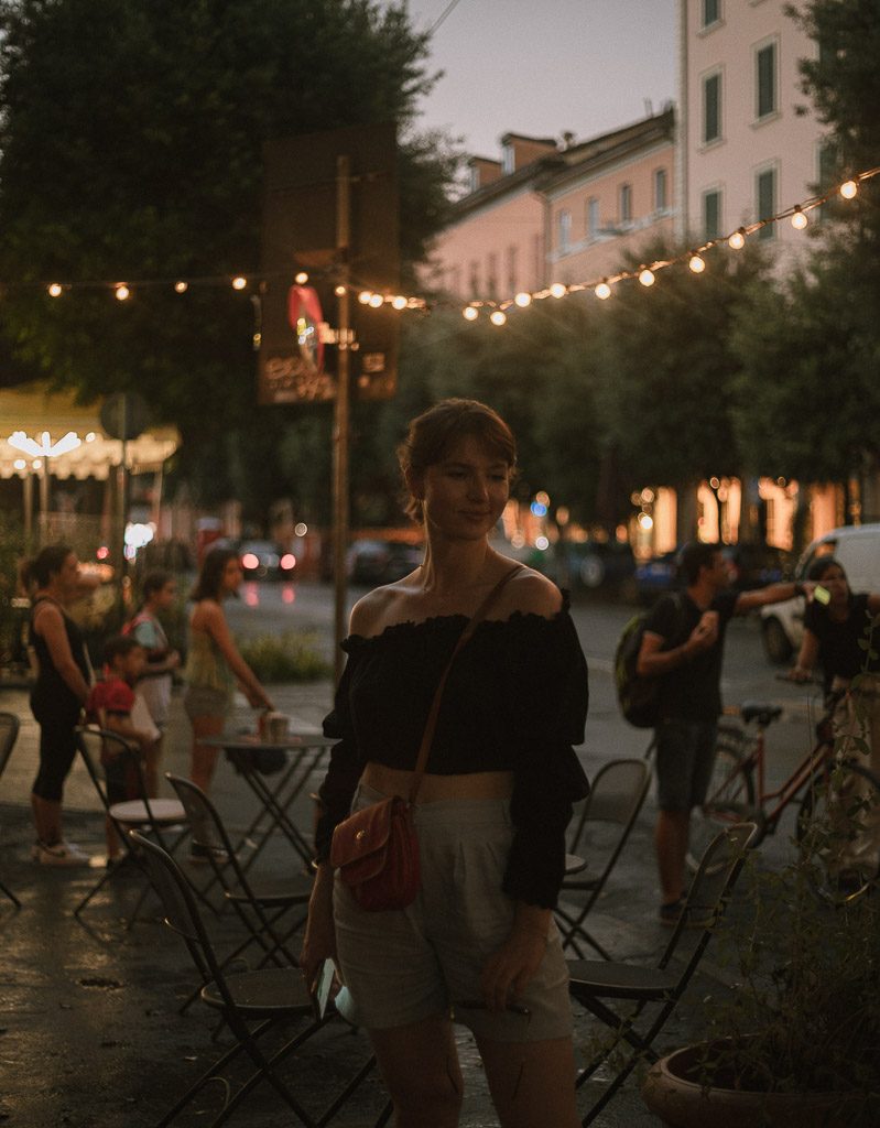 Jak robić dobre zdjęcia? Eksperymentuj z bokeh! Zdjęcie przedstawia dziewczynę sfotografowaną wieczorem na włoskiej ulicy.